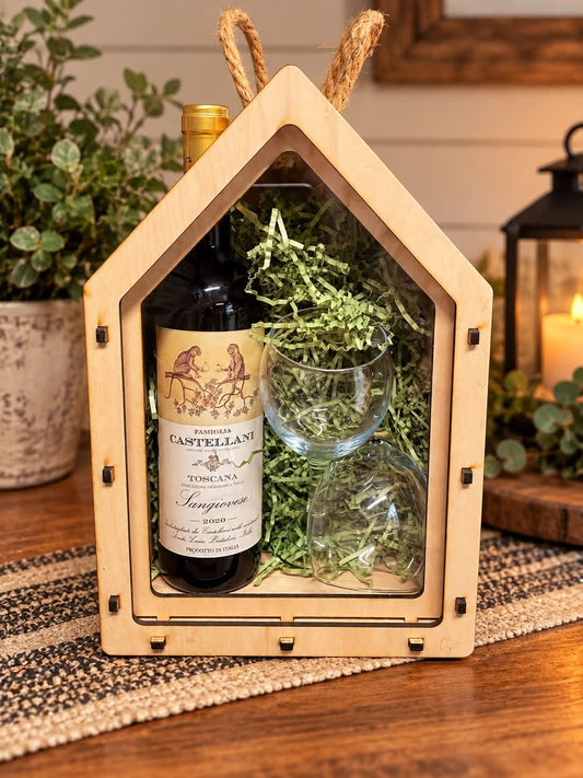 House-shaped maple wine gift box with a clear acrylic sliding lid, shown with a wine bottle, two glasses, and green paper filler.